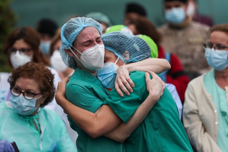 Los trabajadores de la salud que usan mascarillas protectoras reaccionan durante un homenaje a su compañero de trabajo Esteban, un enfermero que murió de la enfermedad del coronavirus frente al Hospital Severo Ochoa en Leganés. (REUTERS / Susana Vera)