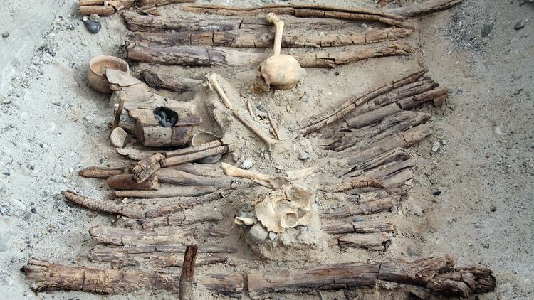 Braseros de madera y un esqueleto encontrado en la tumba M12, tal como quedaron expuestos en las excavaciones de un sitio arqueológico en el oeste de China que proporcionó evidencia sobre la quema de marihuana en un cementerio hace unos 2.500 años (Xinhua Wu/Handout via REUTERS)