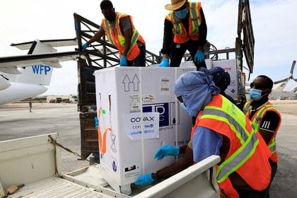 Trabajadores descargan vacunas de AstraZeneca/Oxford en el marco del plan COVAX contra la enfermedad del coronavirus (COVID-19) en el aeropuerto Aden Abdulle Osman en Mogadiscio, Somalia, el 15 de marzo de 2021. REUTERS/Feisal Omar