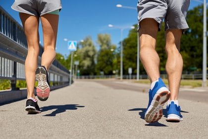 fitness, sport and healthy lifestyle concept - feet of sporty couple running along city road. (Shutterstock)