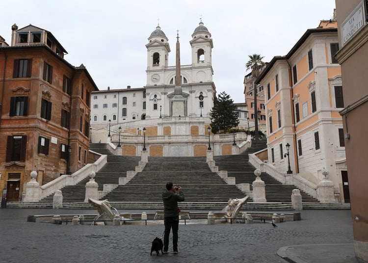 Un hombre toma una fotografía en la turística Via Condotti sin gente alrededor mientras el gobierno italiano continúa con las medidas restrictivas de movimiento para combatir el brote de coronavirus en Roma, Italia, el 14 de marzo de 2020 (REUTERS/Alberto Lingria)