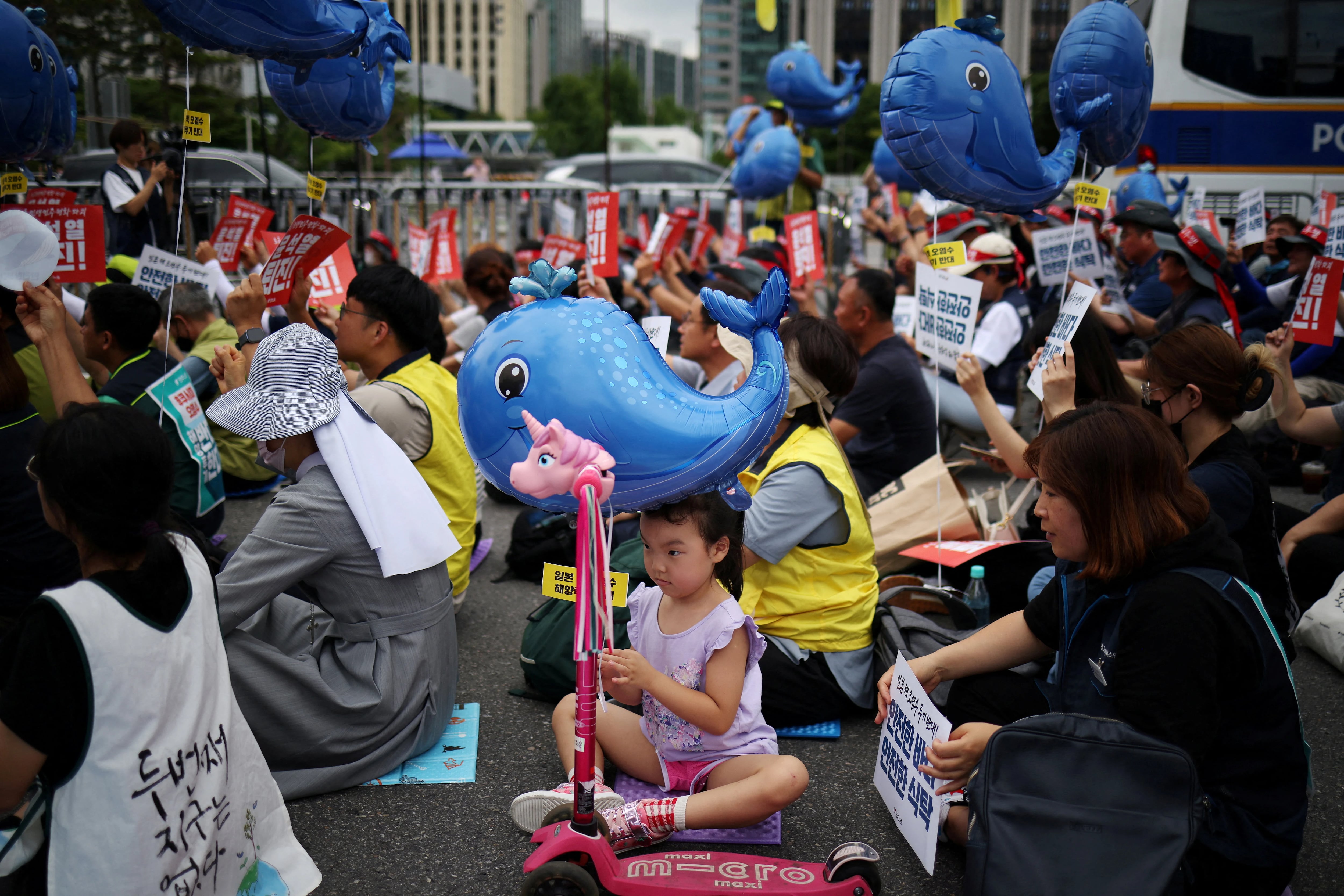 Una niña que sostiene un globo con forma de ballena azul participa en una protesta contra el plan de Japón de descargar agua radiactiva en el océano (REUTERS/Kim Hong-Ji)