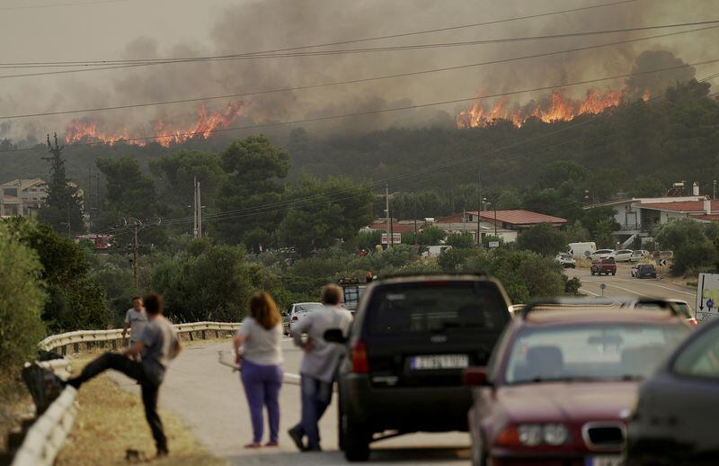 Varias personas miran cómo arde un incendio forestal cerca del pueblo de Agios Sotira (Reuters)