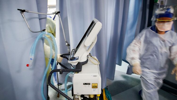 Una enfermera coloca un ventilador en una sala de examen donde un paciente con COVID-19 (AP/John Minchillo)