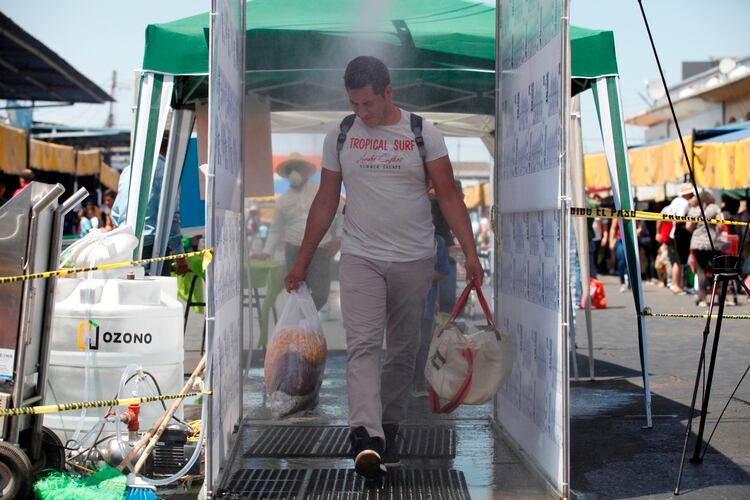 Un hombre cruza un túnel sanitario, que aplica un baño de ozono como medida preventiva ante el COVID-19, este domingo en un mercado de abastos de la ciudad de Guadalajara, en el estado de Jalisco Foto: EFE/Francisco Guasco 