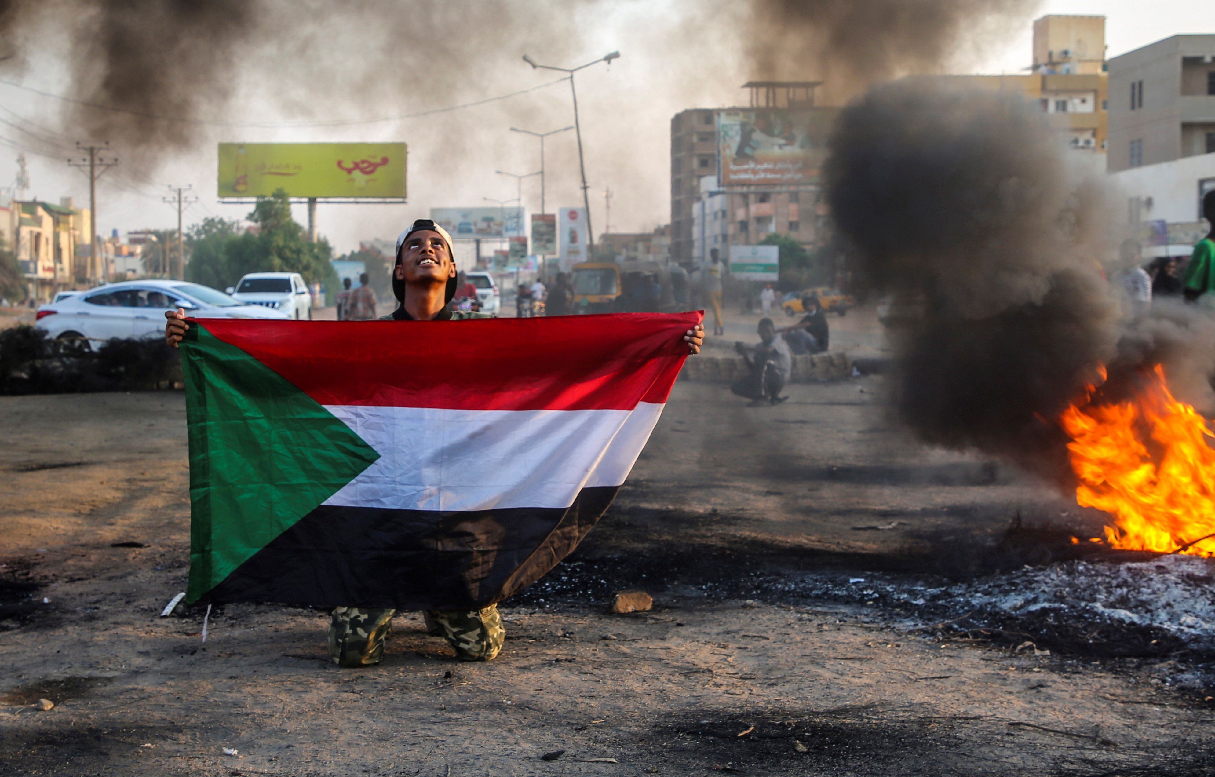 A Sudanese protester holds the national flag next to burning tires during a demonstration in the capital Khartoum, Sudan, on October 26, 2021. EFE / Mohammed Abu Obaid
