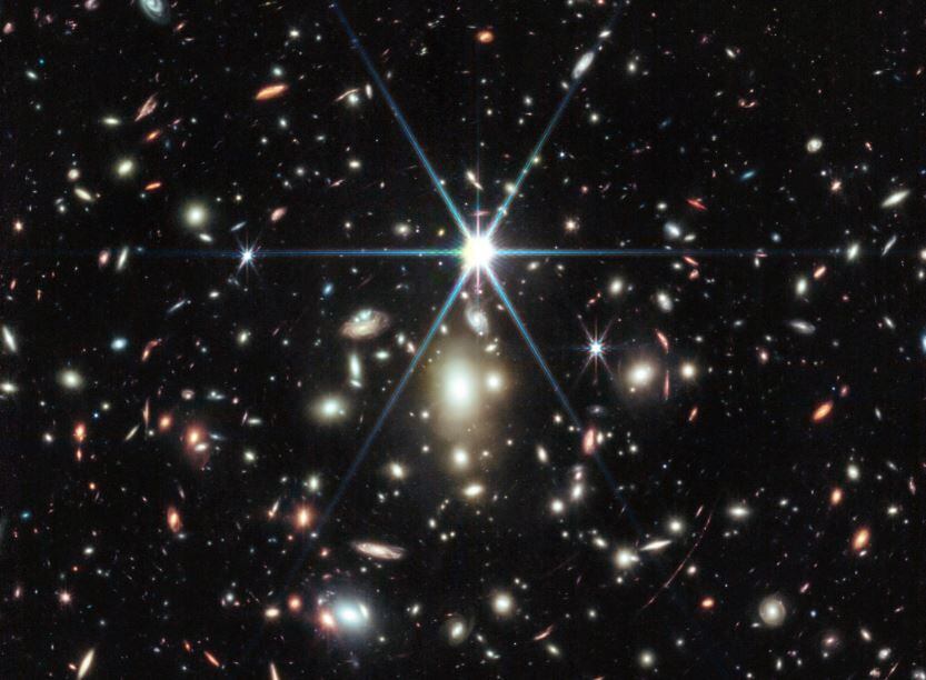 Esta imagen del Webb de un cúmulo de galaxias masivo llamado WHL0137-08 contiene la galaxia más aumentada conocida en los primeros mil millones de años del universo: el Arco del Amanecer, y dentro de esa galaxia, la estrella más distante jamás detectada. (NASA)
