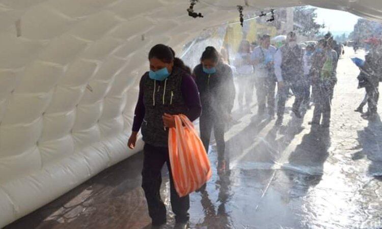 Ciudadanos de Hidalgo tienen que pasar por el túnel sanitizante para ingresar al tianguis dominical. Foto: twitter @online_satelite 