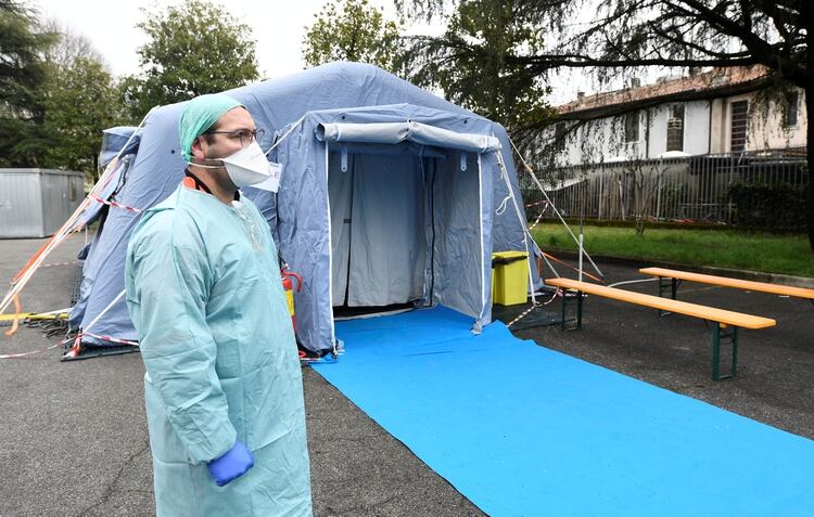 Un trabajador médico con máscara protectora espera en un puesto de control médico a la entrada del hospital Spedali Civili en Brescia (REUTERS / Flavio Lo Scalzo)