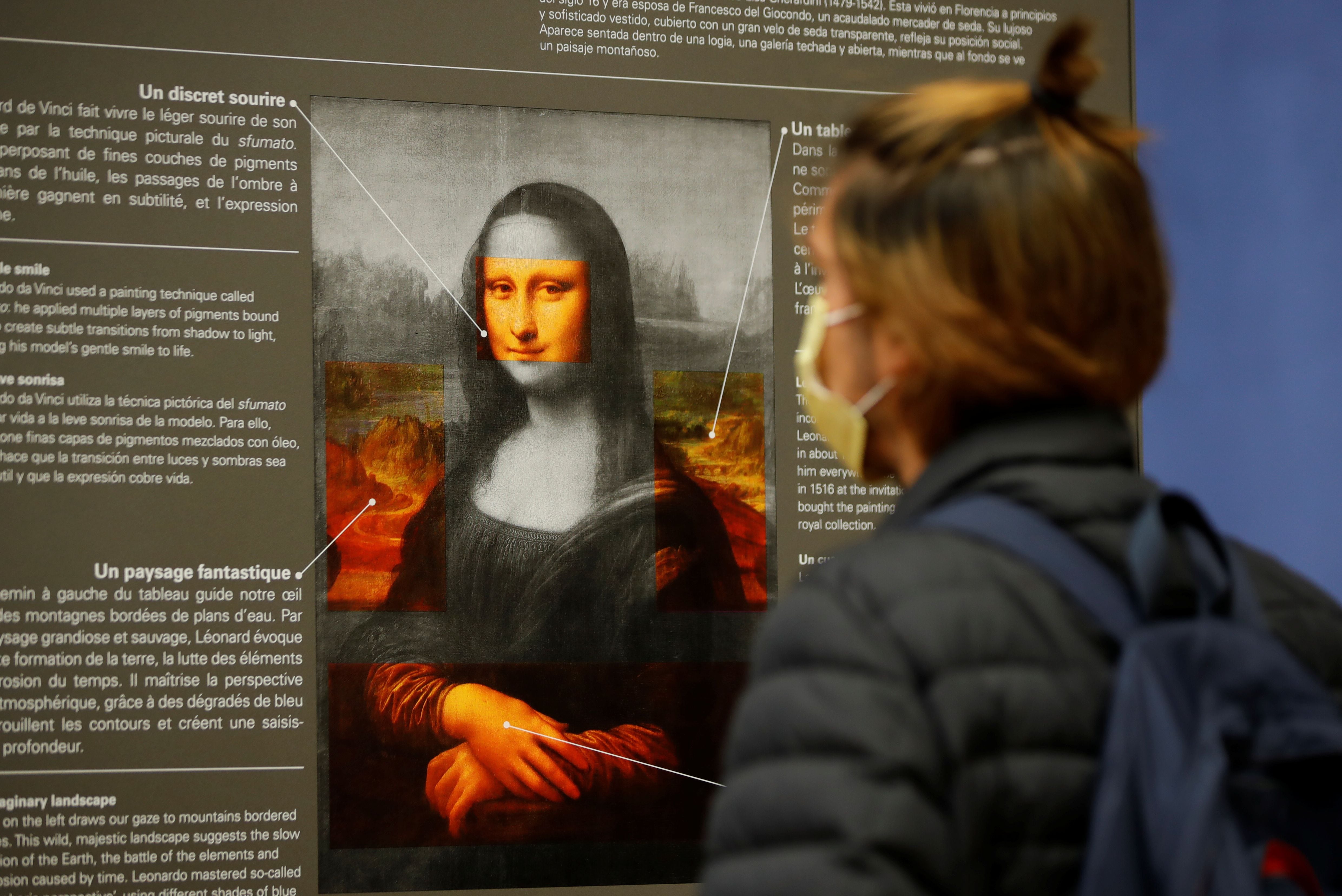 Un visitante, con una mascarilla protectora, mira un cartel con explicaciones sobre el cuadro "Mona Lisa" (La Joconde) de Leonardo Da Vinci en el museo del Louvre de París. REUTERS/Sarah Meyssonnier