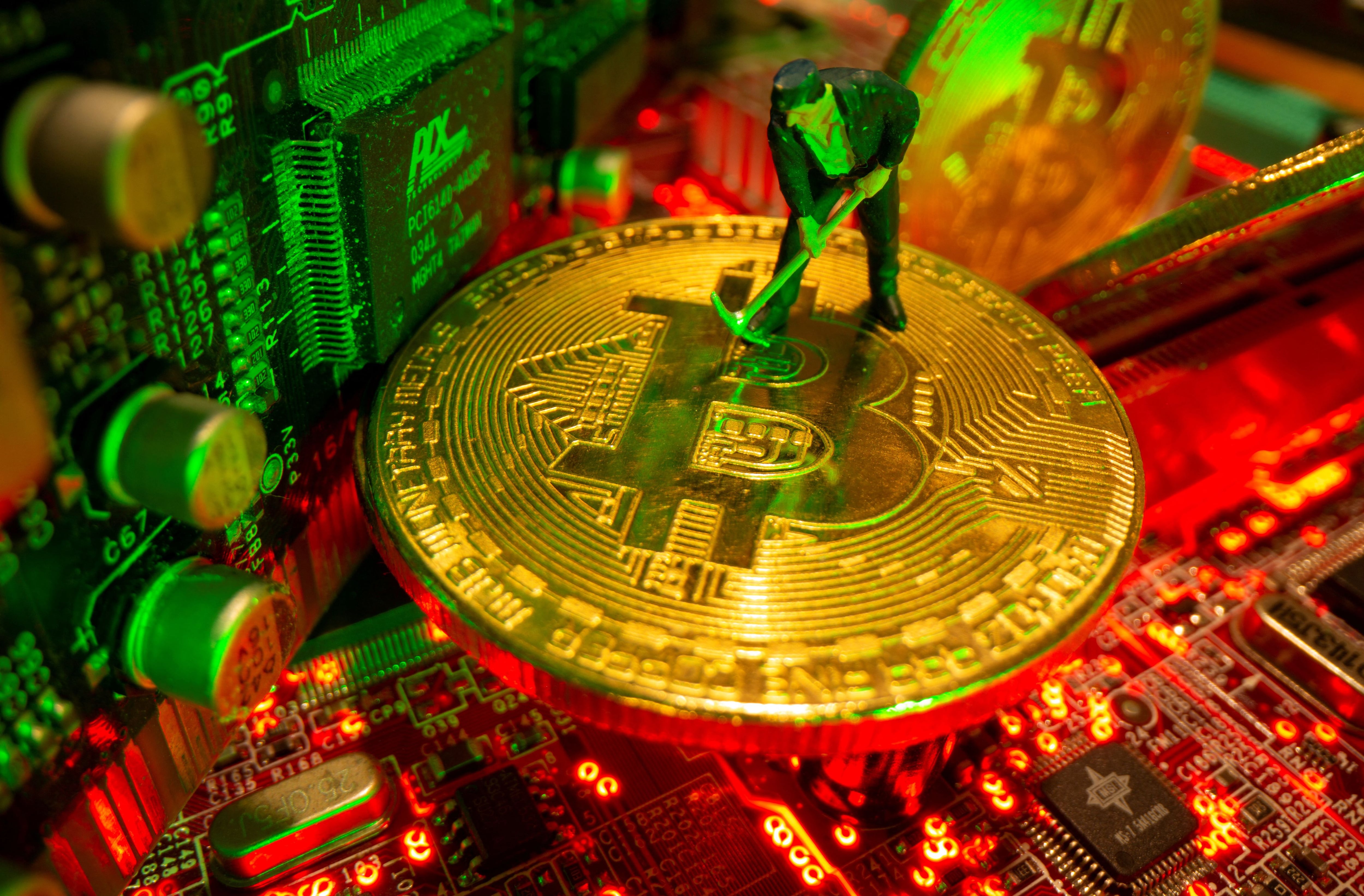 FILE PHOTO: A small toy figure and representations of the virtual currency bitcoin stand on a motherboard in this picture illustration taken May 20, 2021. REUTERS/Dado Ruvic/Illustration/File Photo