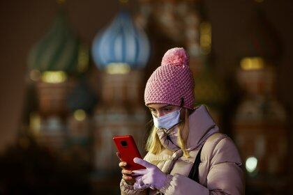 A woman uses her mobile phone before the opening of an outdoor skating rink in the Red Square in Moscow, Russia November 28, 2020. REUTERS/Maxim Shemetov