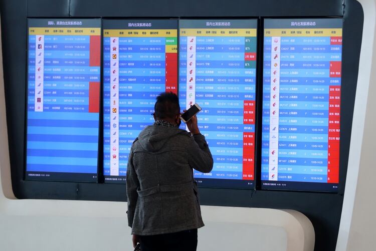 Un hombre observa la pantalla de la terminal aérea de Wuhan que señala que todos los vuelos desde y hacia la ciudad fueron cancelados o desviados (Reuters)