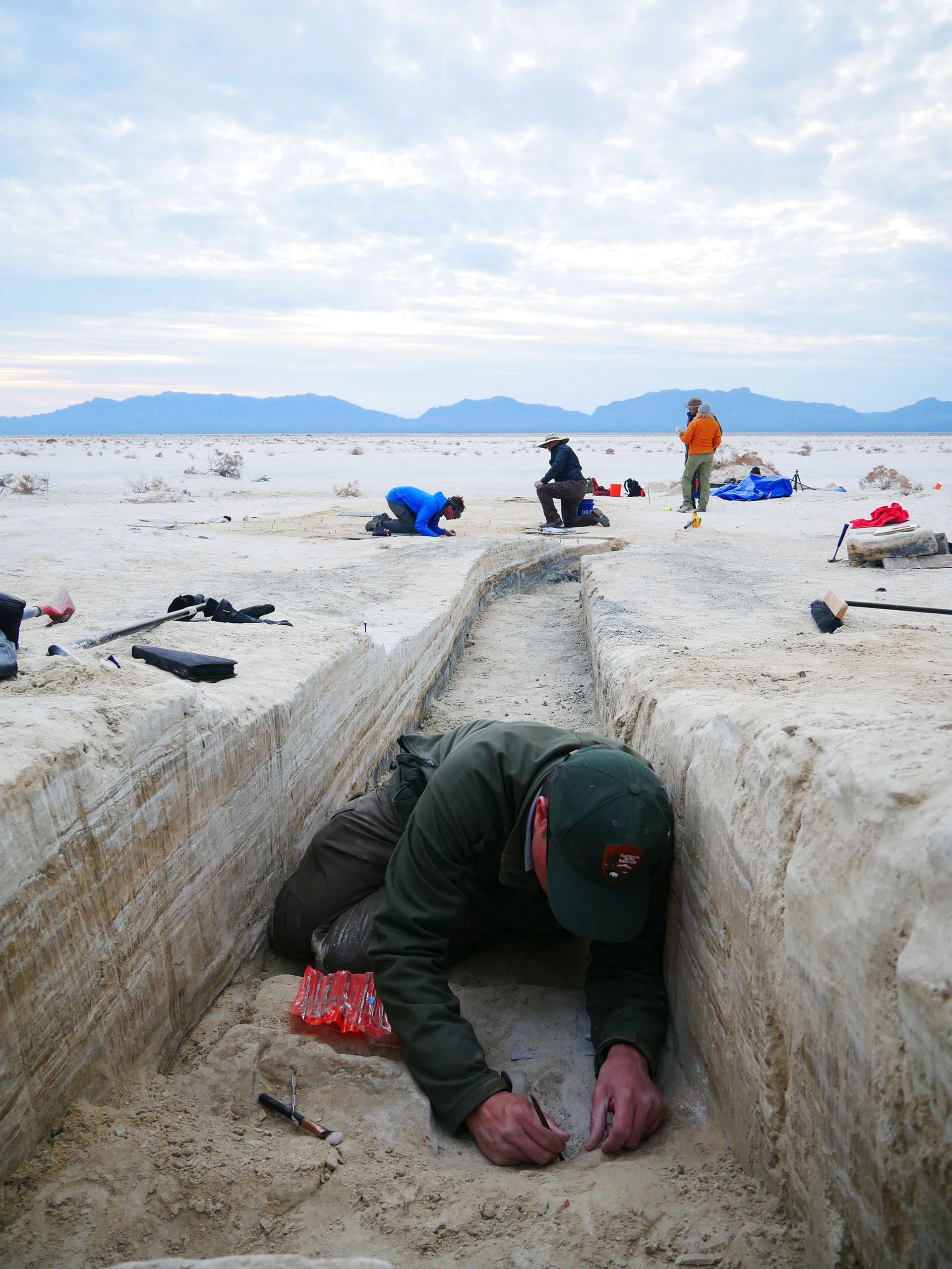 El director del programa de recursos del Parque Nacional White Sands, David Bustos, trabaja en una zanja excavada para exponer las capas de sedimentos en el sitio de estudio. (Crédito:  National Park Service)