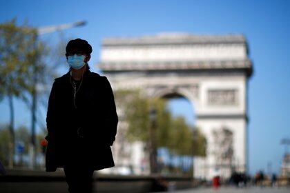 Un hombre con mascarilla camina por la avenida de los Campos Elíseos, cerca del Arco del Triunfo, mientras las tiendas no esenciales permanecen cerradas en todo el país en medio del brote de la enfermedad del coronavirus (COVID-19), en París, Francia, el 23 de abril de 2021. REUTERS/Gonzalo Fuentes