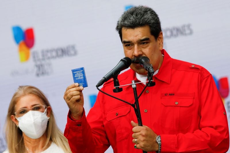 El presidente de Venezuela, Nicolás Maduro, sostiene una pequeña Constitución venezolana mientras pronuncia comentarios junto a su esposa Cilia Flores, luego de emitir su voto durante las elecciones para gobernadores estatales y alcaldes locales, en Caracas, Venezuela November 21, 2021. REUTERS/Fausto Torrealba