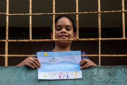 Ana Laura Ramírez Lavandero, de 10 años, sostiene un dibujo en el que expresa su deseo de viajar a la playa, desde el balcón de su casa en La Habana, Cuba. El único momento en que ha podido salir de su casa en casi dos meses fue para ir de emergencia al dentista (AP Foto/Ramón Espinosa )