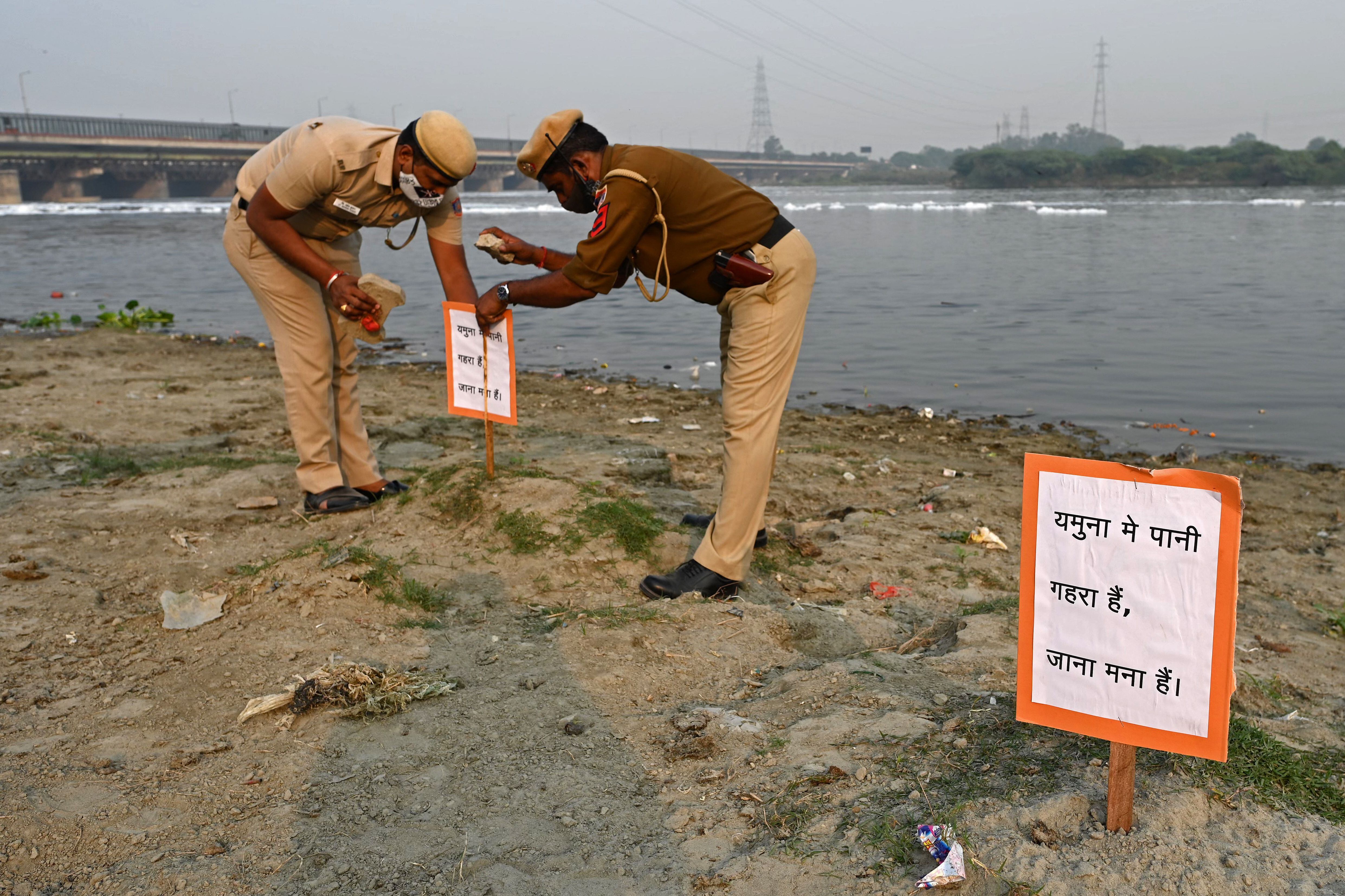 Los policías instalan un cartel que dice "El agua es profunda en Yamuna, no ingrese" para los devotos a lo largo de las orillas del río. (Sajjad HUSSAIN / AFP)