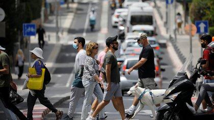 Pedestrians cross a street as Israel rescinds the mandatory wearing of face masks outdoors in the latest return to relative normality, boosted by a mass-vaccination campaign against the coronavirus disease (COVID-19) pandemic, in Tel Aviv, Israel April 18, 2021. REUTERS/Amir Cohen