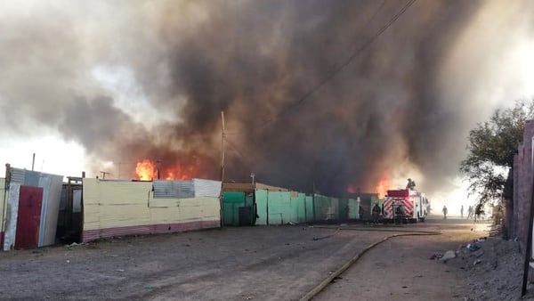 Fotografía cedida que muestra una nube de humo que se eleva entre las casas de la villa miseria, en la región chilena de Antofagasta (EFE)