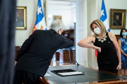 El presidente chileno Sebastián Piñera choca los codos a modo de saludo con la entonces recién nombrada ministra de la Mujer, Macarena Santelices, en la sede de gobierno en Santiago, el 6 de mayo de 2020 (Marcelo Segura/Presidencia Chile/Handout via REUTERS)