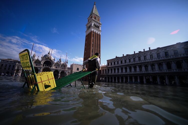 Un hombre tira de un carro a través de la inundada Plaza San Marcos el 14 de noviembre de 2019 en Venecia. (AFP)