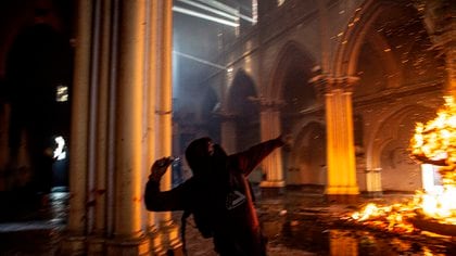 Un manifestante prende fuego dentro de la iglesia de San Francisco de Borja durante enfrentamientos con la policía antidisturbios en la conmemoración del primer aniversario del levantamiento social en Chile, en Santiago, el 18 de octubre de 2020, mientras el país se prepara para un referéndum histórico. (Photo by MARTIN BERNETTI / AFP)