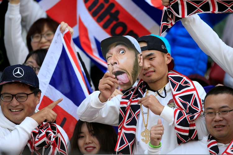 Los fanáticos chinos de Mercedes con una máscara de Lewis Hamilton durante el Gran Premio que se disputa en Shangái (REUTERS)