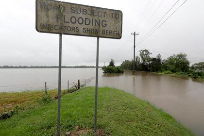 Un cartel advierte de las inundaciones en una carretera mientras la lluvia cae en Windsor, al noroeste de Sydney. (AP Photo/Rick Rycroft)