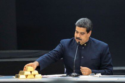 Foto de archivo del dictador venezolano Nicolas Maduro, tocando una pila de lingotes de oro durante una rueda de prensaa en el Palacio de Miraflores en Caracas (REUTERS/Marco Bello)