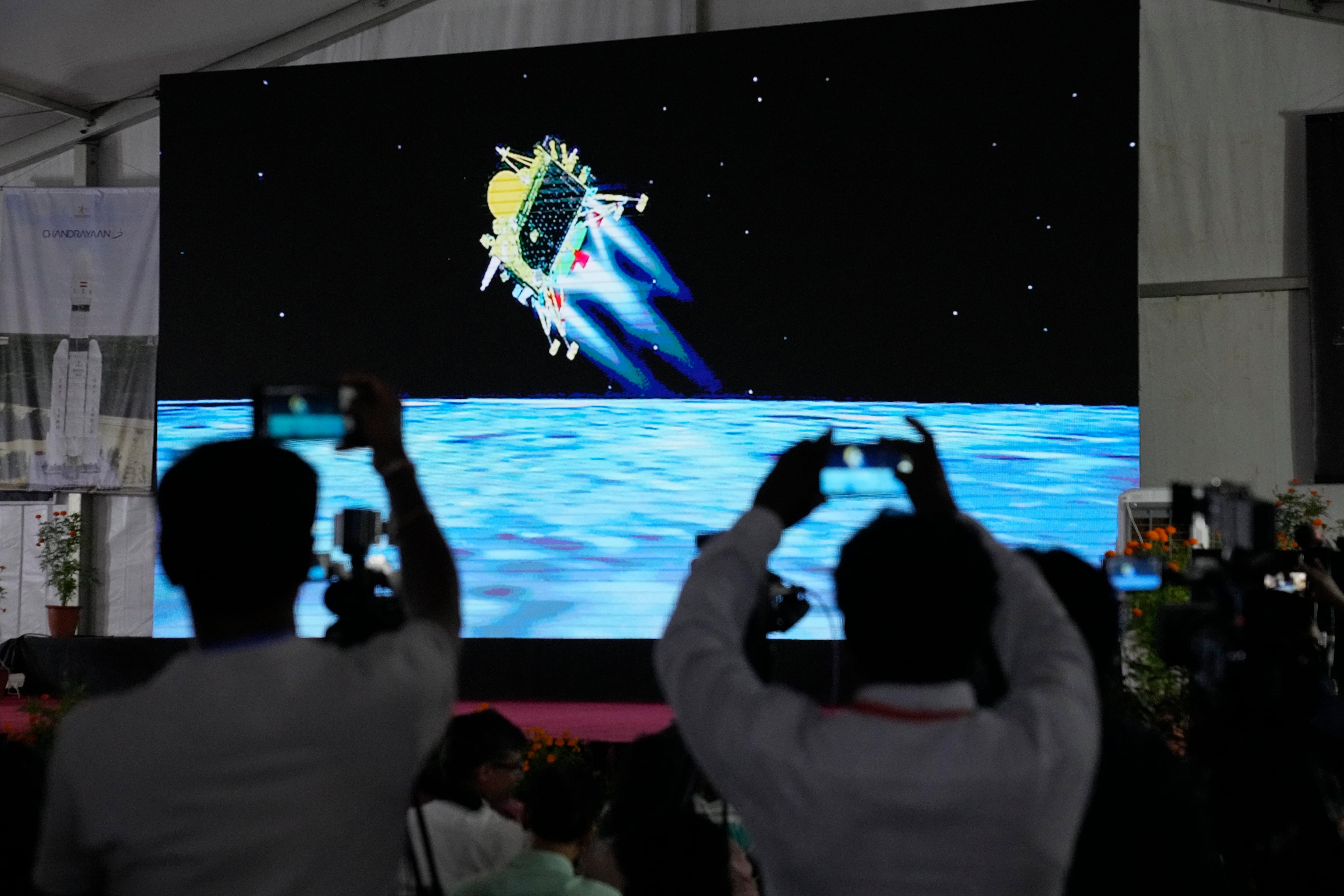 Periodistas filman la transmisión en vivo del alunizaje de la nave espacial india Chandrayaan-3 en el centro de telemetría, rastreo y comando de ISRO en Bengaluru, India, miércoles 23 de agosto de 2023. India es el cuarto país que logra alunizar, y el primero que lo hace cerca del polo sur de la luna. (AP Foto/Aijaz Rahi)