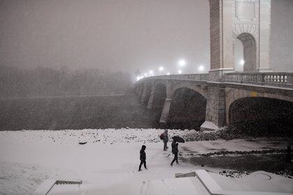 Jessica Armitage, James Mackarabage y Jayden Fisher caminan junto al río Susquehanna durante las fuertes nevadas el 16 de diciembre de 2020 en Wilkes Barre, Pennsylvania. (Mark Makela / Getty Images / AFP)