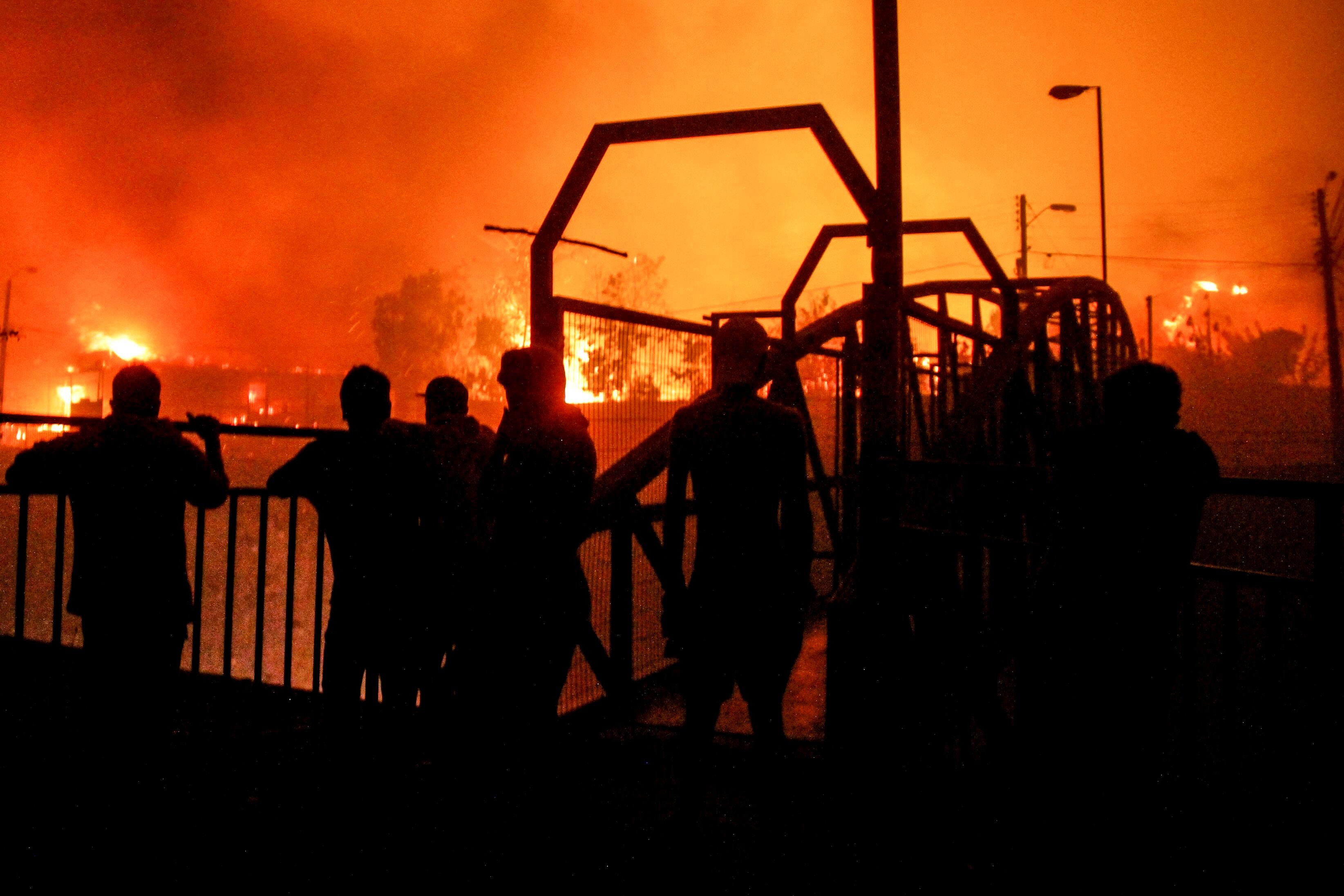 Un grupo de vecinos observa mientras las llamas devoran un edificios en Viña del Mar, Chile, el 2 de febrero de 2024 (AP Foto/Cristobal Basaure)