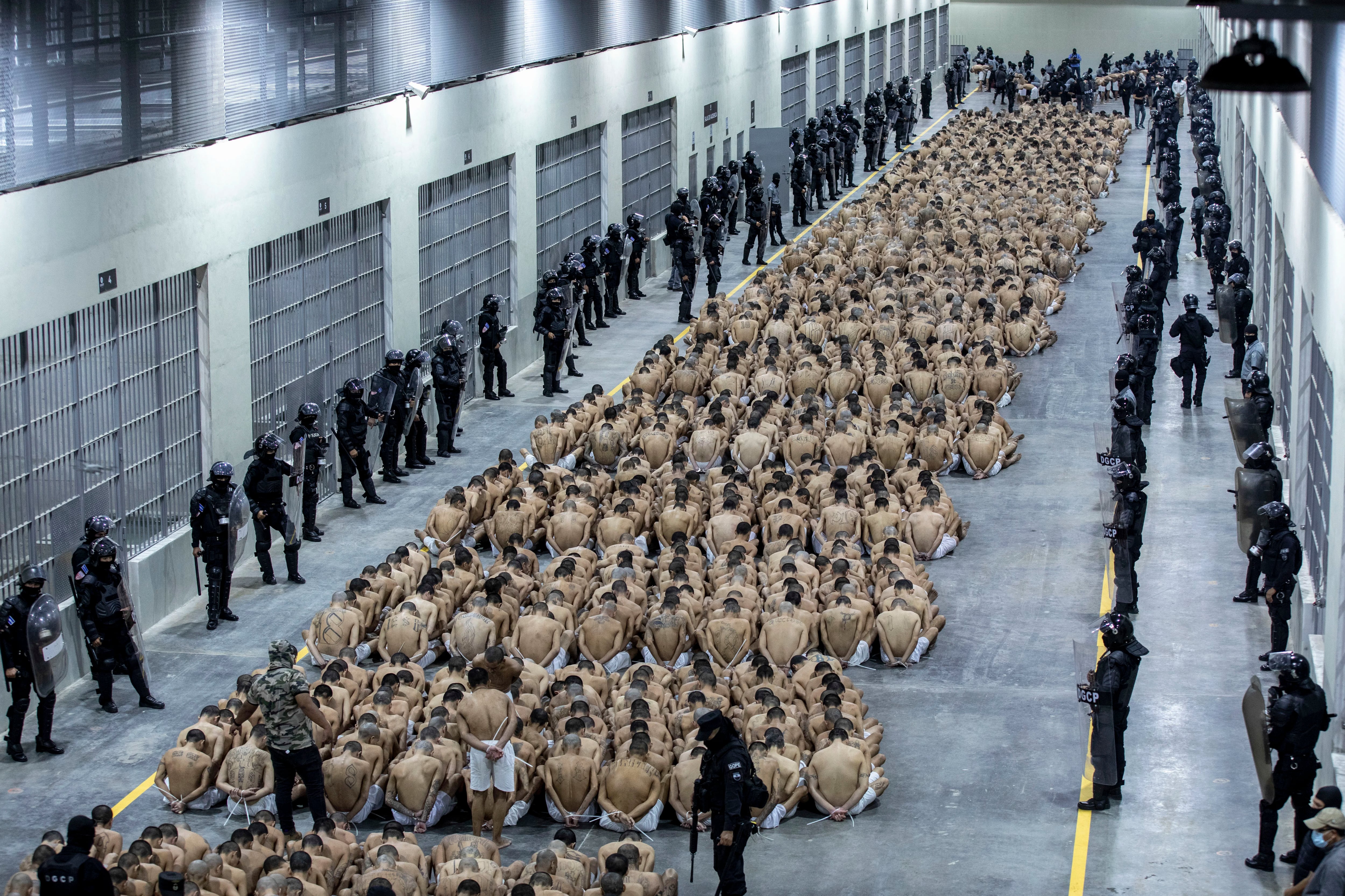 En esta foto proporcionada por la oficina de prensa de la presidencia de El Salvador, los presos identificados por las autoridades como pandilleros están sentados en el piso de la prisión del Centro de Confinamiento contra el Terrorismo en Tecoluca, El Salvador, el miércoles 15 de marzo de 2023. (Oficina de prensa de la presidencia de El Salvador, vía AP )