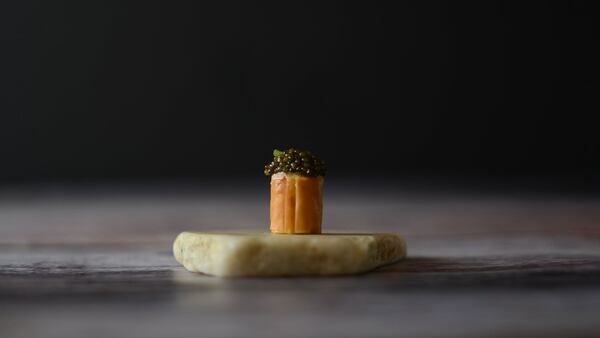 Snack de salmón con caviar servido sobre un trozo de mármol blanco.  (Alo’s)