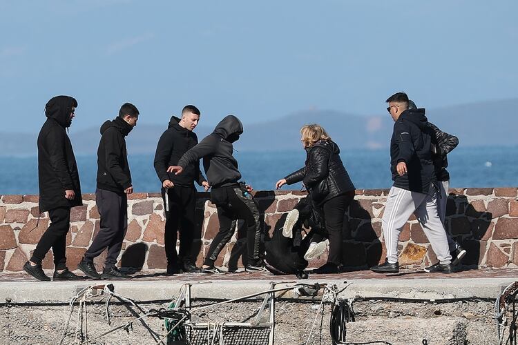 Lugareños evitan que los migrantes desembarquen en el puerto de Thermi y golpean a un periodista, mientras una mujer intenta detenerlos, en la isla de Lesbos, Grecia (REUTERS/Stringer)