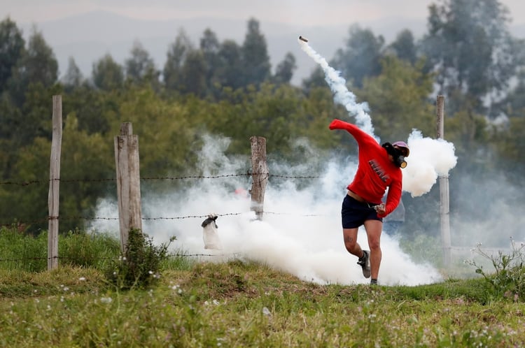 Un manifestante vuelve a lanzar un proyectil de gas lacrimógeno lanzado por las fuerzas de seguridad durante las protestas en Lasso (REUTERS/Carlos Garcia Rawlins)