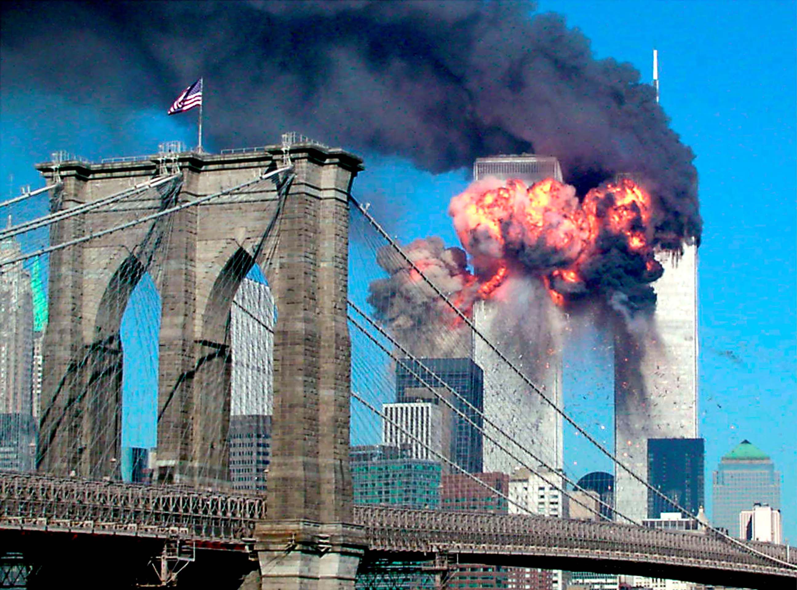 A segunda torre pega fogo minutos após o impacto.  Essa cena podia ser vista da ponte do Brooklyn, mas o que aconteceu ainda era desconhecido.  Os alarmes estavam começando a soar na cidade de Nova York.