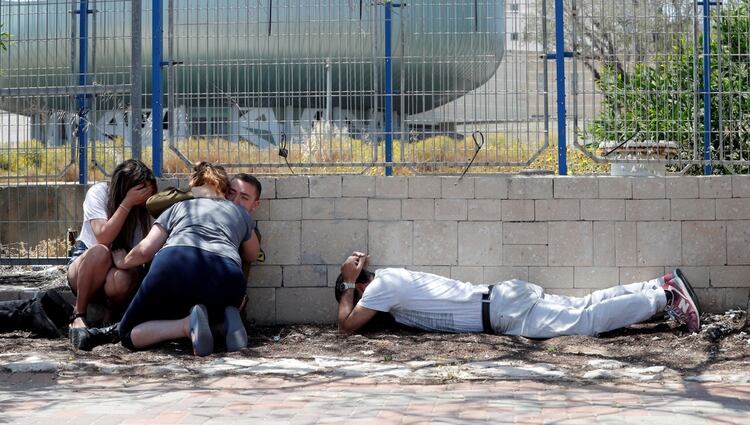 Los israelíes se esconden mientras escuchan sirenas que advierten de la llegada de cohetes desde Gaza, durante las hostilidades transfronterizas, en la ciudad israelí de Ashkelon, al sur del país, el 5 de mayo de 2019. (REUTERS)