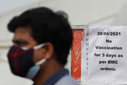 Un hombre con mascarilla pasa frente a un cartel en el que se lee "No habrá vacunaciones durante 3 días por orden de la Corporación Municipal de la Gran Bombay (BMC)” en inglés en el exterior de un centro de vacunación en Bombay, India, el 30 de abril de 2021. REUTERS/Francis Mascarenhas