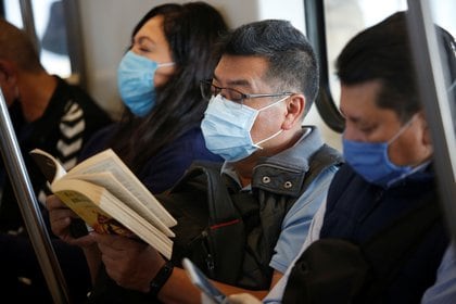 Un hombre con una máscara protectora lee un libro mientras viaja en el metro de la CDMX (Foto: Reuters)