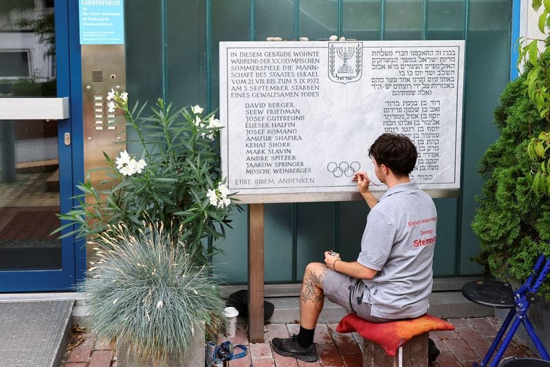 Un joven renueva una placa conmemorativa de los 11 atletas israelíes asesinados por militantes palestinos durante los Juegos Olímpicos de 1972, en el lugar de la toma de rehenes en la antigua Villa Olímpica de Múnich, Alemania