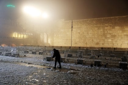 Un hombre limpia la nieve del suelo junto al Muro Occidental, el lugar de oración más sagrado del judaísmo, en la ciudad vieja de Jerusalén, el 18 de febrero de 2021. REUTERS / Ronen Zvulun