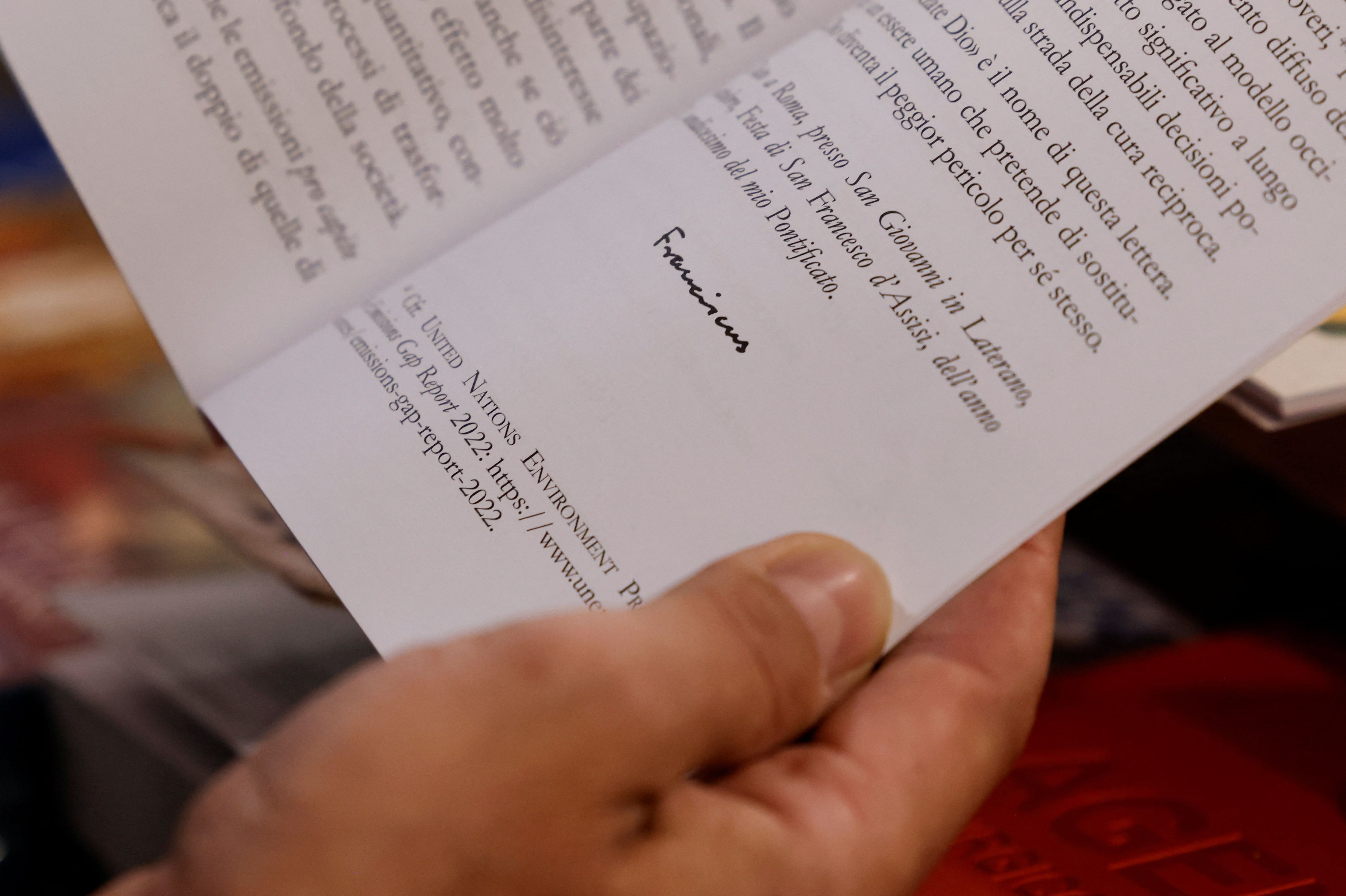 Una persona sostiene el "Laudate Deum", escrito por el papa Francisco, en una librería cerca del Vaticano en Roma, Italia, el 4 de octubre de 2023. REUTERS/Remo Casilli