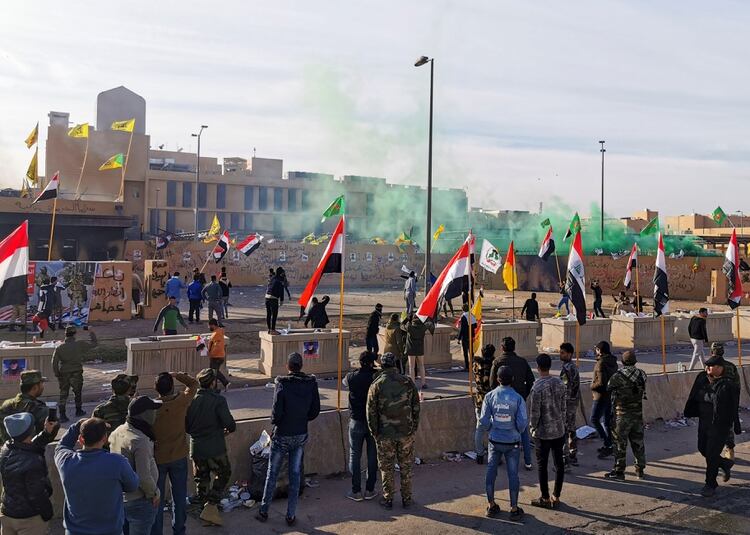 Mikicianos descargan el contenido de una bengala de humo verde en la entrada del predio de la embajada de EEUU en Irak (REUTERS/Thaier al-Sudani)