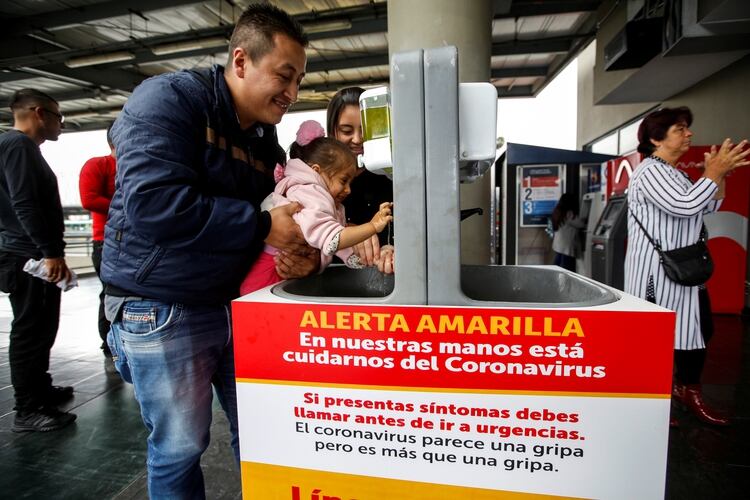 n hombre lava las manos de su hija en uno de los lavaderos públicos instalados en la Terminal de Transporte, como medida preventiva contra la propagación del nuevo coronavirus (COVID-19), en Bogotá, Colombia, el 13 de marzo de 2020