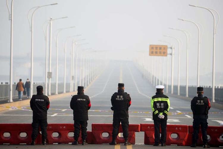 Oficiales de policía montan guardia en el puesto de control ubicado en el puente del río Jiujiang Yangtze, en la región de Hubei. Foto: REUTERS/Thomas Peter - RC2SQE9UMKZ5