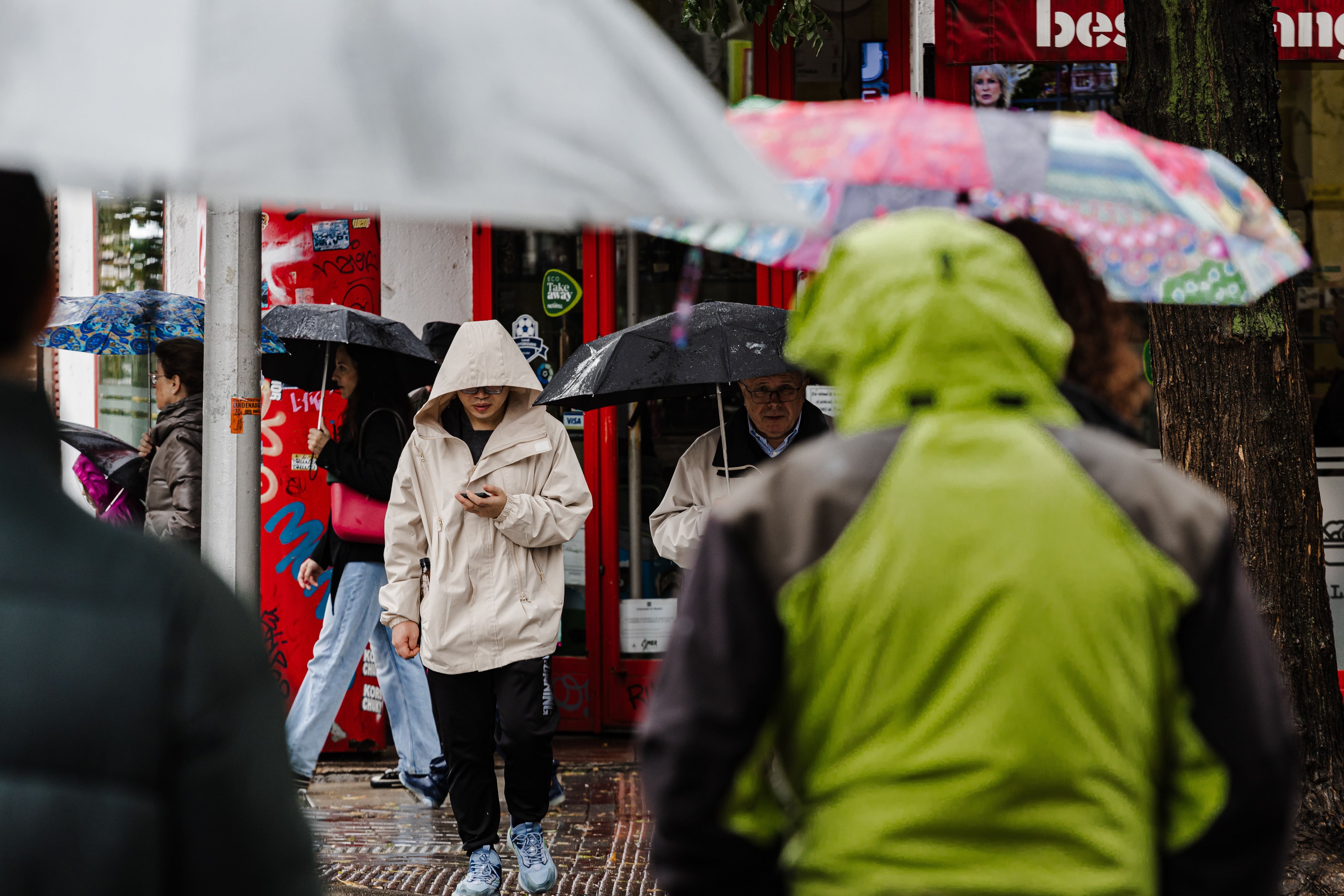 Varias personas se protegen de la lluvia con paraguas en Madrid. (Carlos Luján / Europa Press)