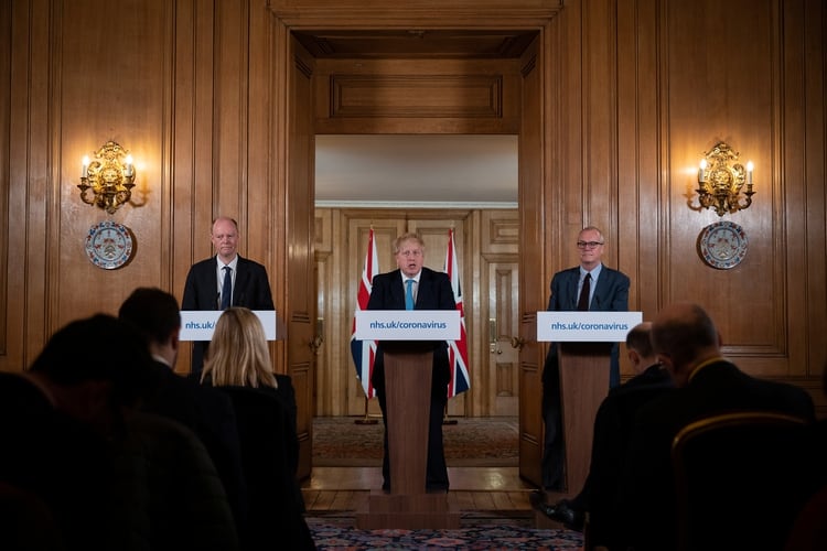 El Director Médico de Reino Unido, el Profesor Chris Whitty (izquierda) y el Asesor Científico Jefe Patrick Vallance miran al Primer Ministro Británico Boris Johnson durante la conferencia de prensa (Leon Neal/Pool vía REUTERS)