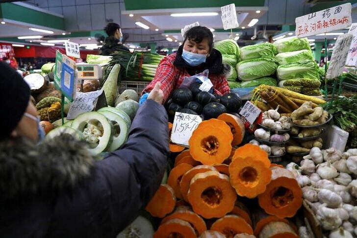 Una persona comprando en un puesto de verduras en un mercado de Beijing, China. REUTERS/Tingshu Wang